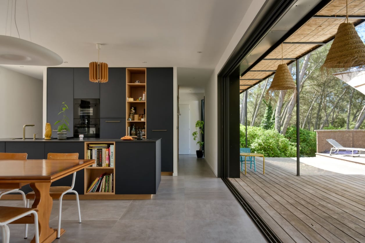 Cuisine contemporaine ouverte avec mobilier en bois et grandes baies vitrées.