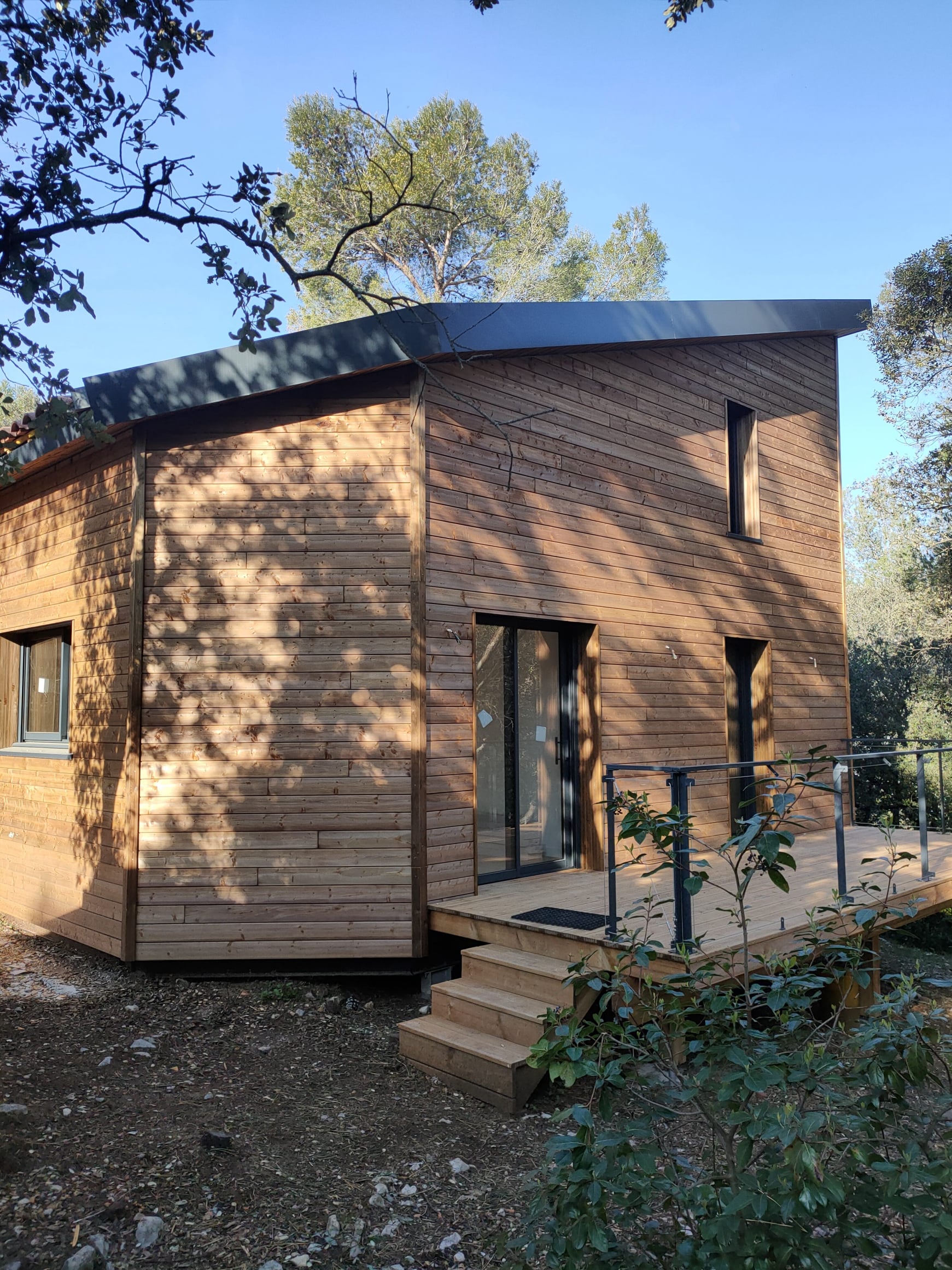 Maison ossature bois  conçue par Home habilis avec structure métallique sur un terrain en pente.