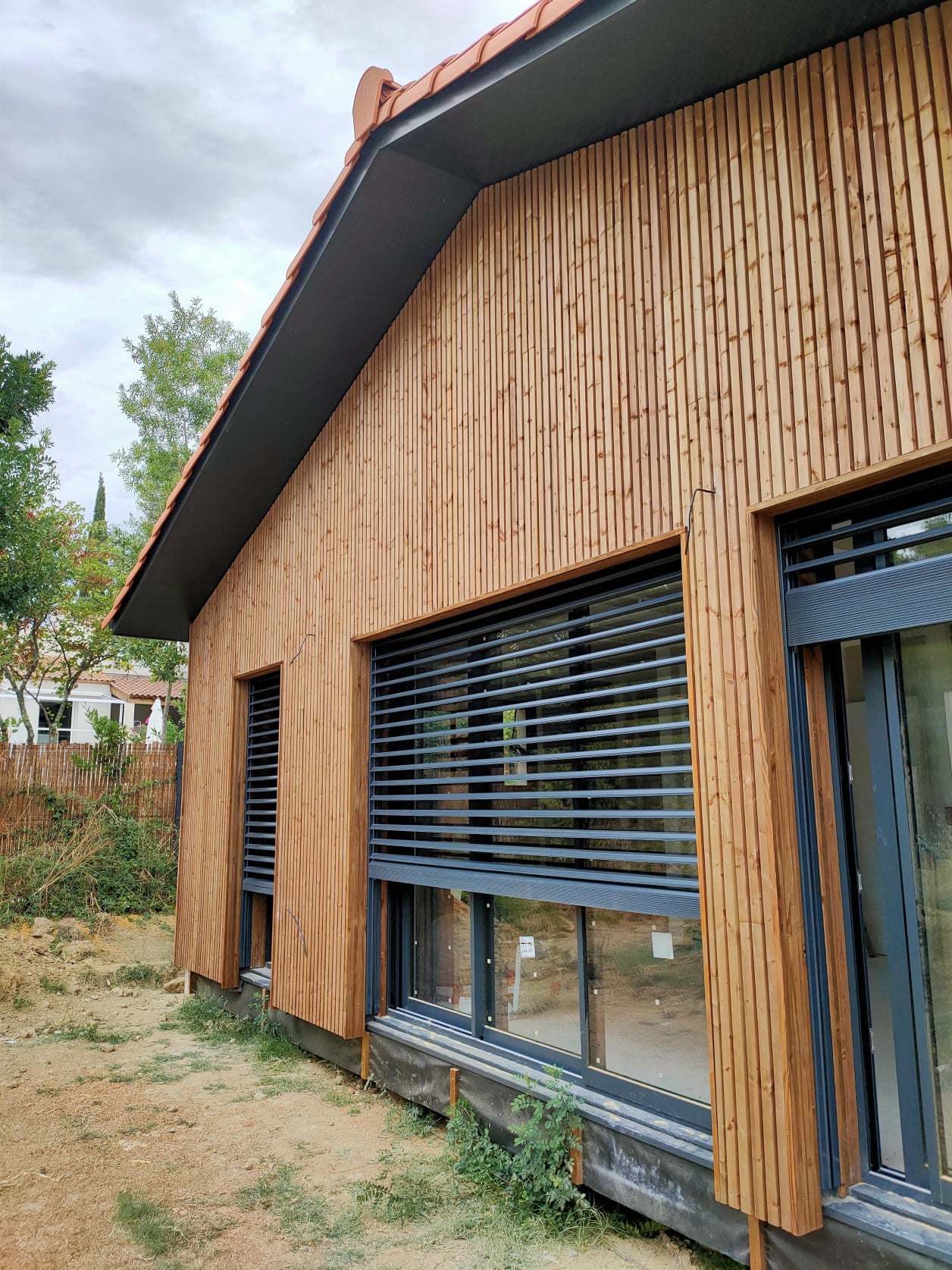 Maison contemporaine ossature bois avec  façade bardage vertical  bois à claire voie.