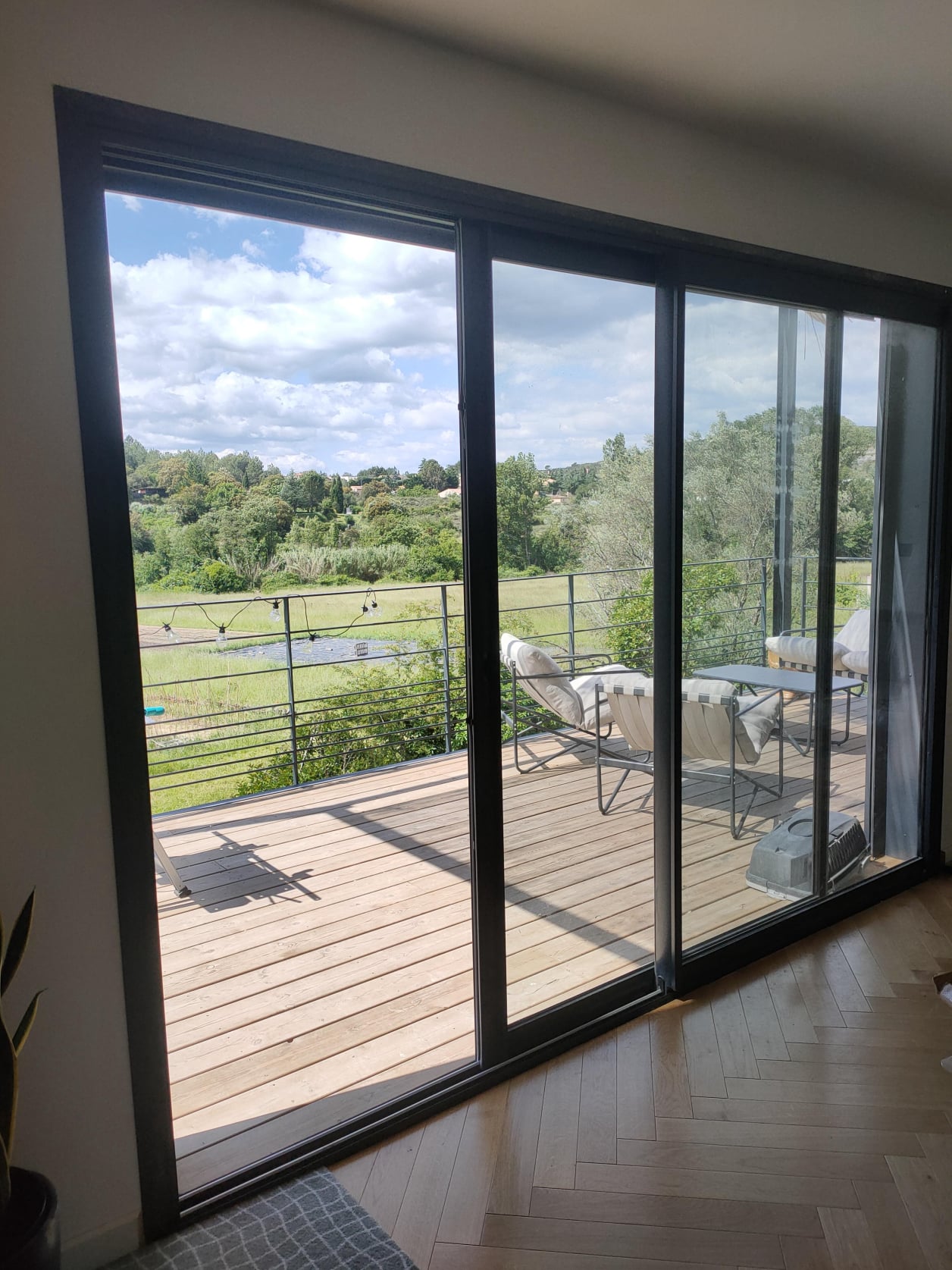 Construction d'une maison à ossature bois réalisée par Home Habilis dans le Gard. Baie vitrée 3 vantaux sur terrasse suspendue bois.